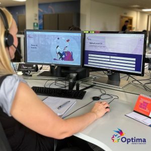 Photo shows a person at their desk. The desk has two computer screens on it.