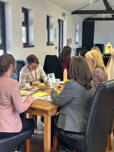 People at tables completing tasks at the Worcestershire Workplace Wellbeing at Work Well Live Better Showcase delivered by Optima UK